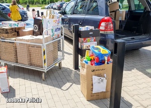Wózek z zabawkami przy samochodzie.