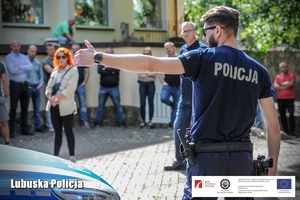 Policjant tłumaczy wykonywane czynności zgromadzonym uczestnikom konferencji