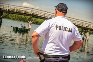 Policjant spoglądający na łódź nad jeziorem.