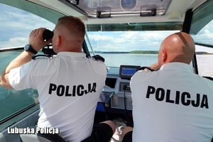 Policjanci z łodzi obserwują akwen przez lornetkę