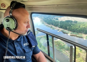 Policjant obserwuje rzekę z helikoptera