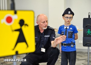 policjant z chłopcem w miasteczku ruchu drogowego
