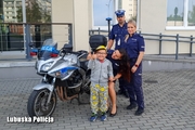 Mały chłopiec stojący przy policjantach i motocykla.