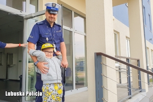 Mały chłopiec stojący przy policjancie drogówki.