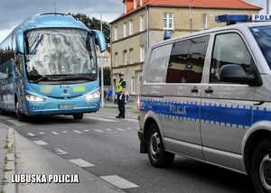 Policyjny radiowóz prowadzi autokar kibiców.