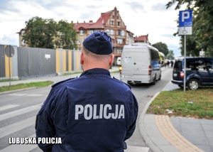 Policjant, a w tle autokar jadący jezdnią.