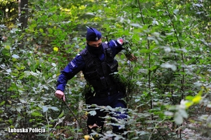 Policjant przedziera się przez zarośla