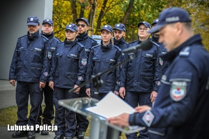 policjant czytający na mównicy i policjanci w tle