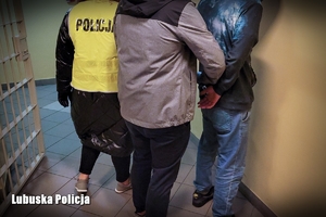 Przeprowadzenie zatrzymanego mężczyzny przez nieumundurowanych policjantów.