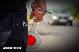 Ręka policjant a z lizakiem do zatrzymywania pojazdów a w tle samochód