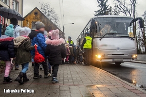 Dzieci stojące przy autokarze, a obok nich policjant.