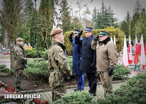 Przedstawiciele służb mundurowych oddają honor przed pomnikiem.