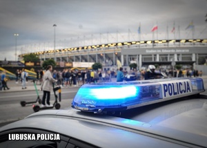 Policyjny radiowóz na tle stadionu żużlowego.