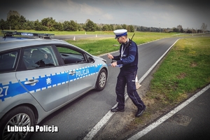 Policjant drogówki daje znak do startu radiowozem przy pokonywaniu toru przeszkód.