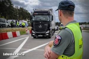 Funkcjonariusz Służby Celno - Skarbowej, a w tle pojazd ciężarowy.