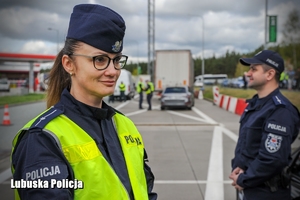 Policjantka, a w tle inny policjant stojący przy radiowozie.