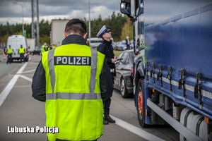 Policjant Policji niemieckiej, a w tle policjant z Polski podczas kontroli drogowej.