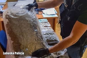 policjant podnosi zabezpieczone narkotyki