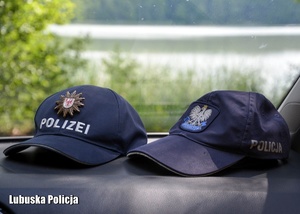 Czapki policyjne z Polski i Niemiec w radiowozie.