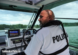 Policjant podczas prowadzenia motorówki nad jeziorem.