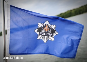Flaga z policyjnym logiem na tle jeziora.