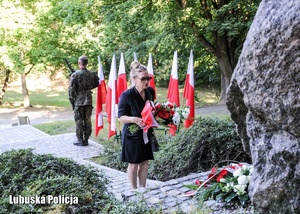 Kobieta składa kwiaty przed pomnikiem.