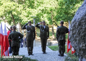 Żołnierze oddają hołd przed pomnikiem.
