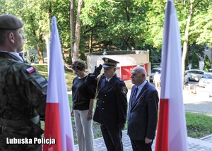 Osoby oddają hołd przed pomnikiem.