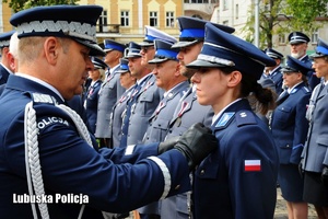 I Zastępca Komendanta Głównego Policji przypina odznaczenie policjantce.