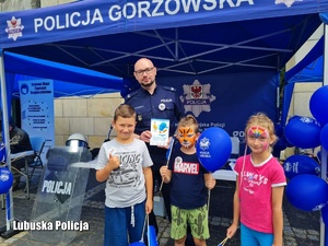 Policjant z dziećmi na stoisku profilaktycznym.