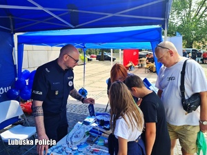 Policjanci na stoisku profilaktycznym z dziećmi.