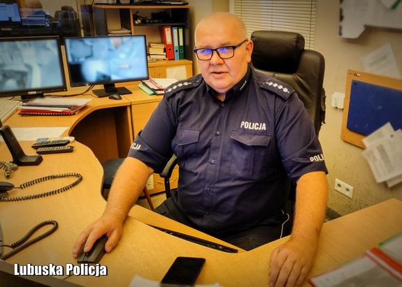 Policjant - dyżurny jednostki - siedzący przy biurku.