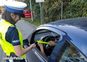 Policjantka wręcza odblask kierującemu pojazdem.