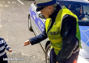 Policjantka wręcza dziecku element odblaskowy.