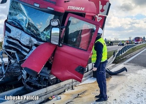 Policjant podczas przeprowadzania oględzin samochodu ciężarowego, który uczestniczył w zdarzeniu drogowym.