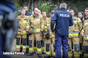 Policjanci oraz strażacy podczas odprawy związanej z poszukiwaniami osoby zaginionej.