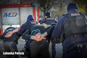 Policjanci prowadzą zatrzymanych w trakcie działania