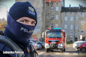 Policjant z wozem strażackim w tle