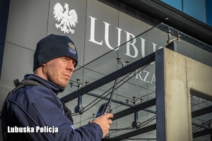 Policjant z widocznym w tle budynkiem Urzędu Wojewódzkiego