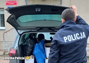 policjant stoi przy samochodzie z otwartym bagażnikiem