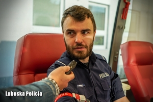 Policjant podczas udzielania wywiadu przy oddawaniu krwi.