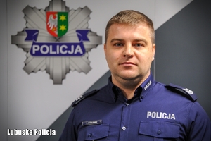 policjant stoi przed banerem