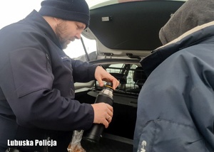 policjant przekazuje herbatę bezdomnemu