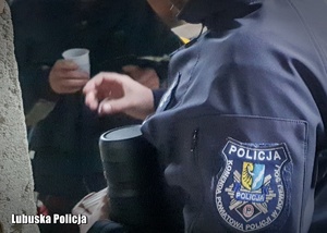 policjant przekazuje herbatę bezdomnemu