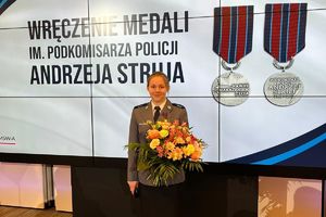 wyróżniona policjantka stoi przed telebimem