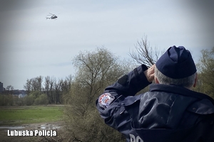 policjant spogląda na helikopter lecący w powietrzu