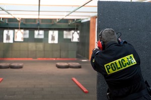 Policjant strzela do tarczy zza zasłony.