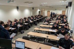 Policjanci rozwiązują test w sali konferencyjnej.