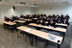 Policjanci rozwiązują test na sali konferencyjnej.