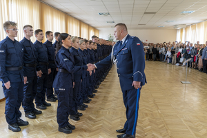 Komendant wita się symbolicznie z nowo przyjętymi policjantami